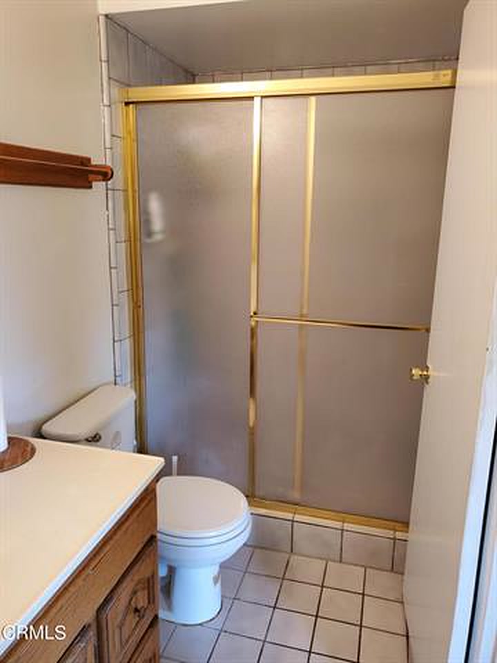The primary bath in 2022: a gold-framed frosted glass shower enclosure, tile surround and tile flooring.
