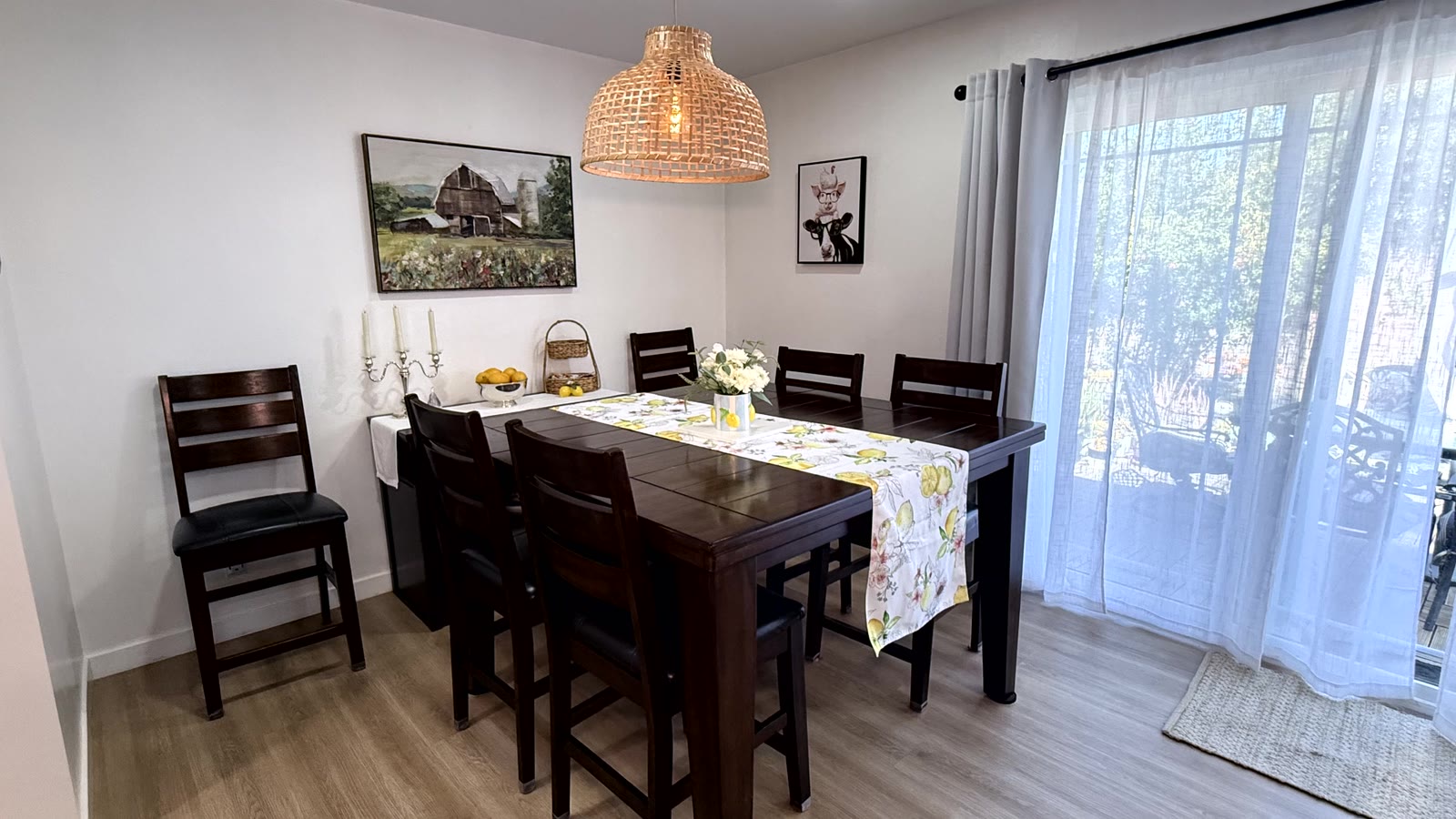 Separate dining room with a woven rattan dome pendant over a dark wood table, and a large sliding glass door to the rear yard dressed with sheer curtains.