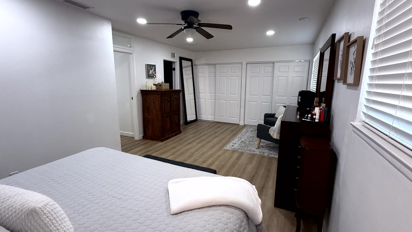 Primary bedroom closet wall showing two separate runs of white six-panel closet doors, with a full-length floor mirror alongside.